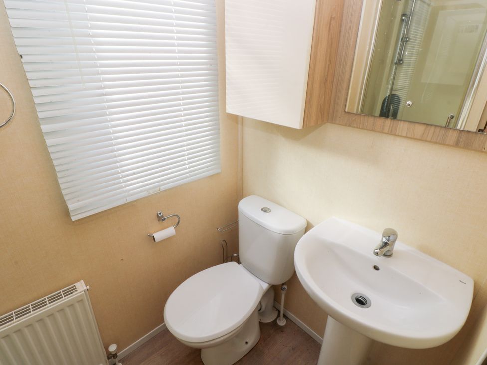 A bathroom with a toilet and sink at Under cliff caravan Ferryside