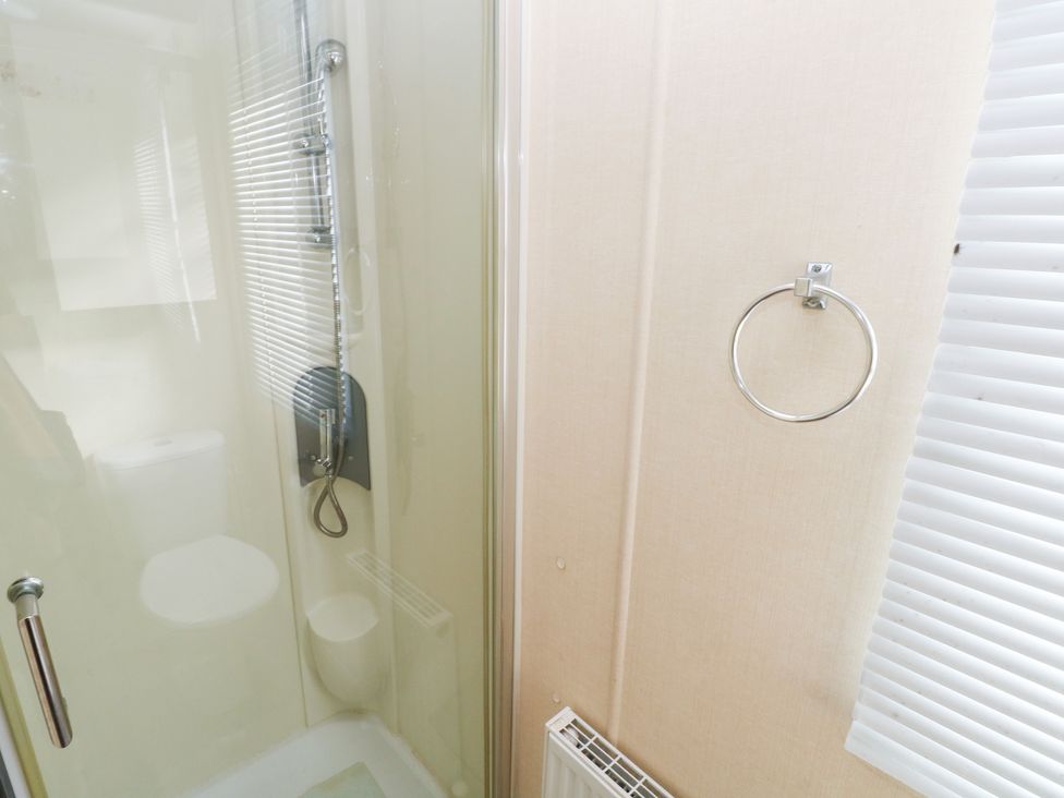 A bathroom with a shower and toilet at Under cliff caravan Ferryside