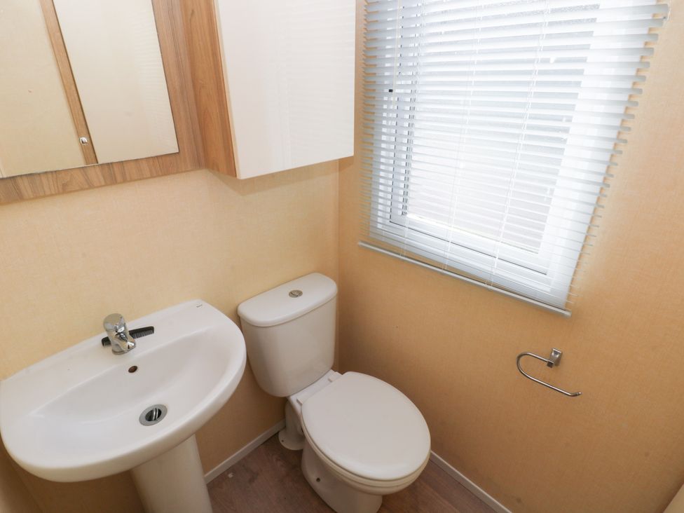A bathroom with a sink and toilet at Under cliff caravan Ferryside