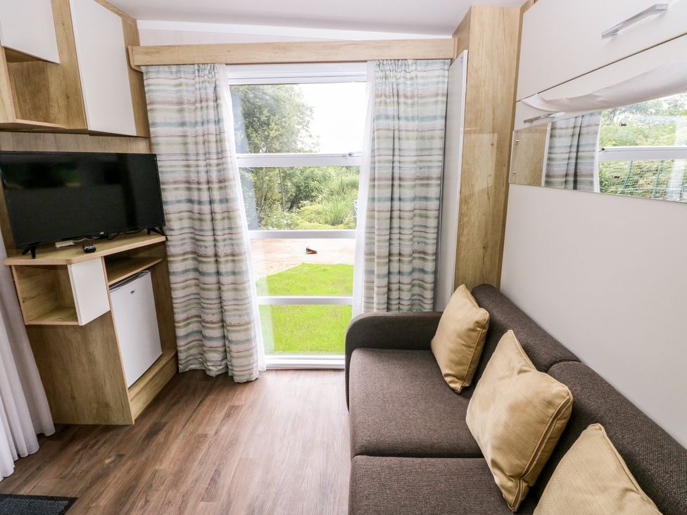 A living room with a television, sofa, and window at The Pod in Ferryside