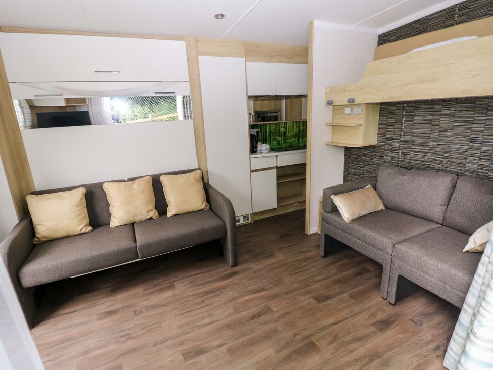 A living room with two sofas and a kitchen area at The Pod in Ferryside