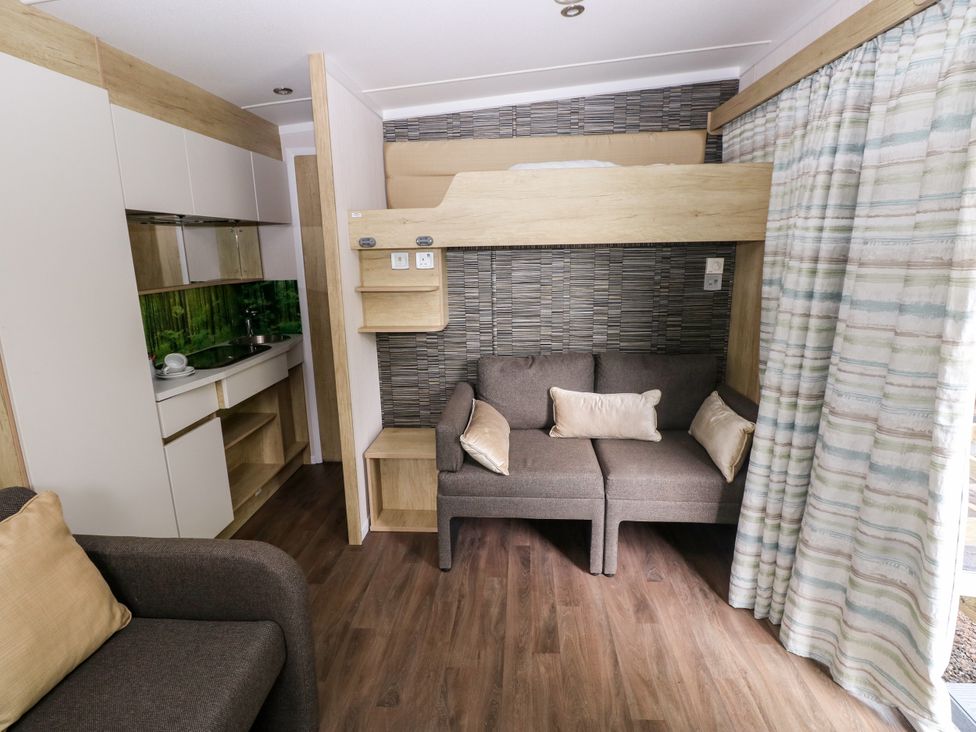 A living room with a sofa and a kitchenette at The Pod in Ferryside