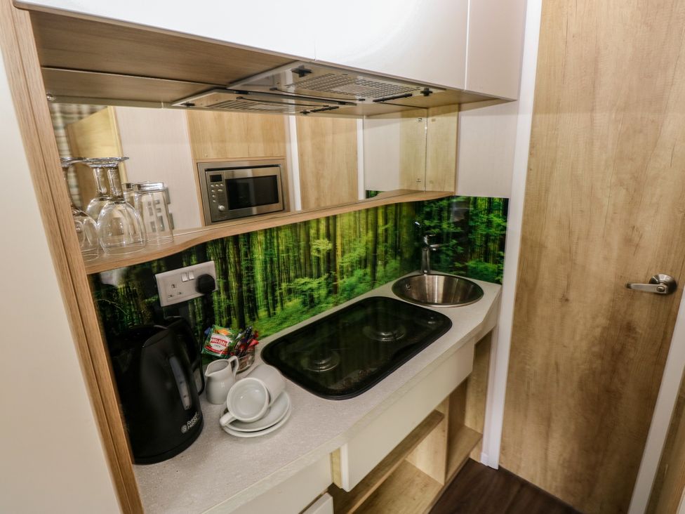 A kitchen with a cooking hob, sink, and appliances at The Pod in Ferryside