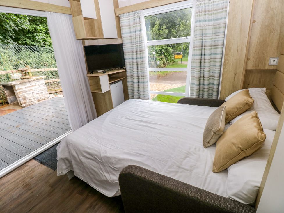 A bedroom with a bed and television at The Pod in Ferryside
