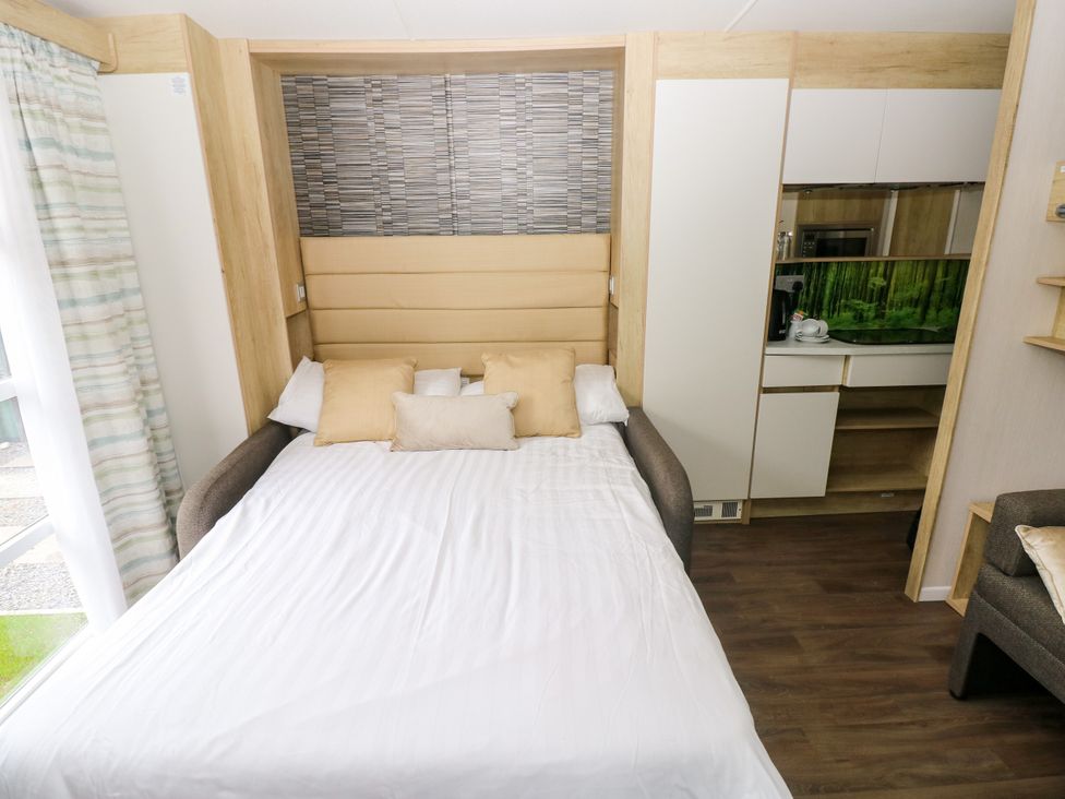 A bedroom with a bed and kitchenette at The Pod in Ferryside