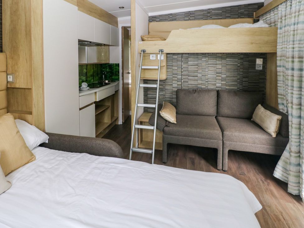 A bedroom with a bunk bed and kitchenette at The Pod in Ferryside