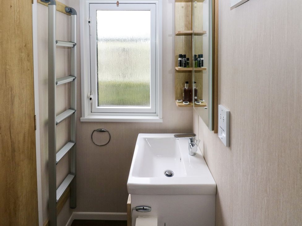 A bathroom with a sink and a mirror at The Pod in Ferryside