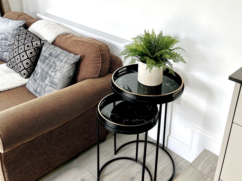 A living room with a sofa, nested tables, and a plant at The Dove Cot in Ambleside