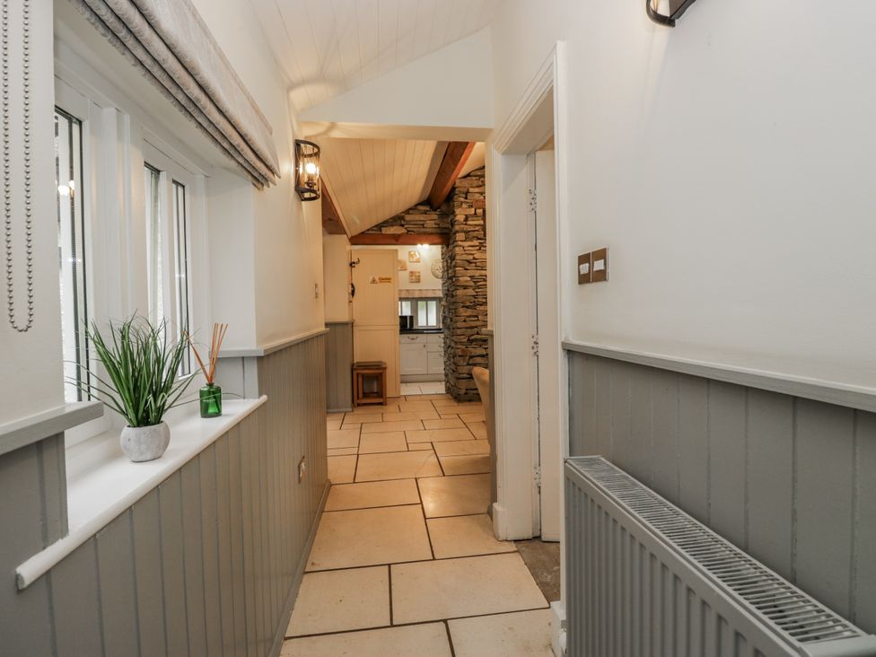 A hallway with plants and a view into the kitchen at The Dove Cot in Ambleside