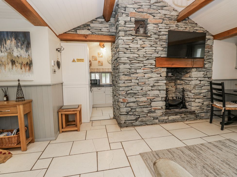 A living room with a stone wall and television at The Dove Cot in Ambleside
