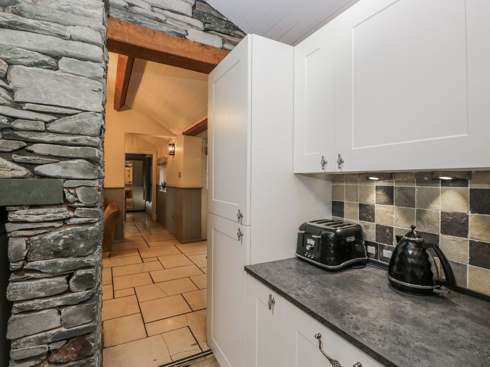 A kitchen with white cabinets and appliances at The Dove Cot in Ambleside