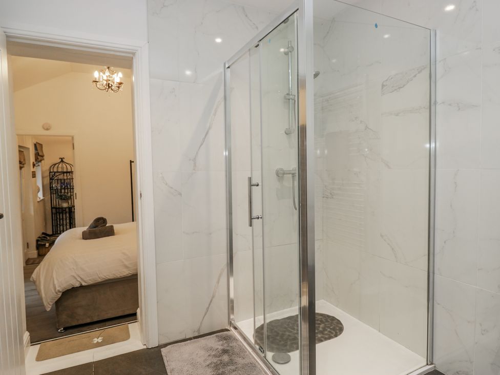 A bathroom with a shower and a doorway leading to a bedroom at The Dove Cot in Ambleside