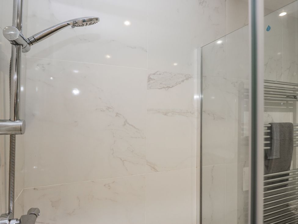 A shower stall with a chrome showerhead and towel rack at The Dove Cot in Ambleside
