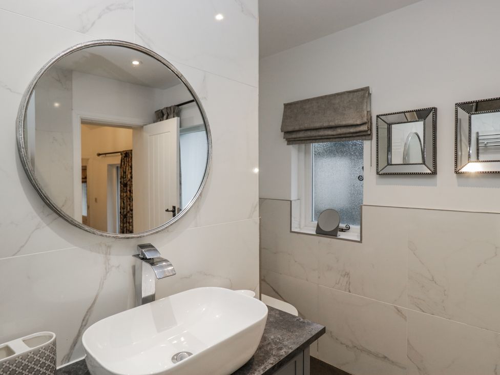 A bathroom with a round mirror and a sink at The Dove Cot in Ambleside