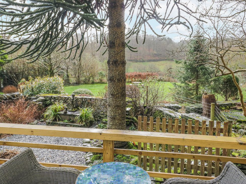 A garden view with a tree and stone wall at The Dove Cot in Ambleside