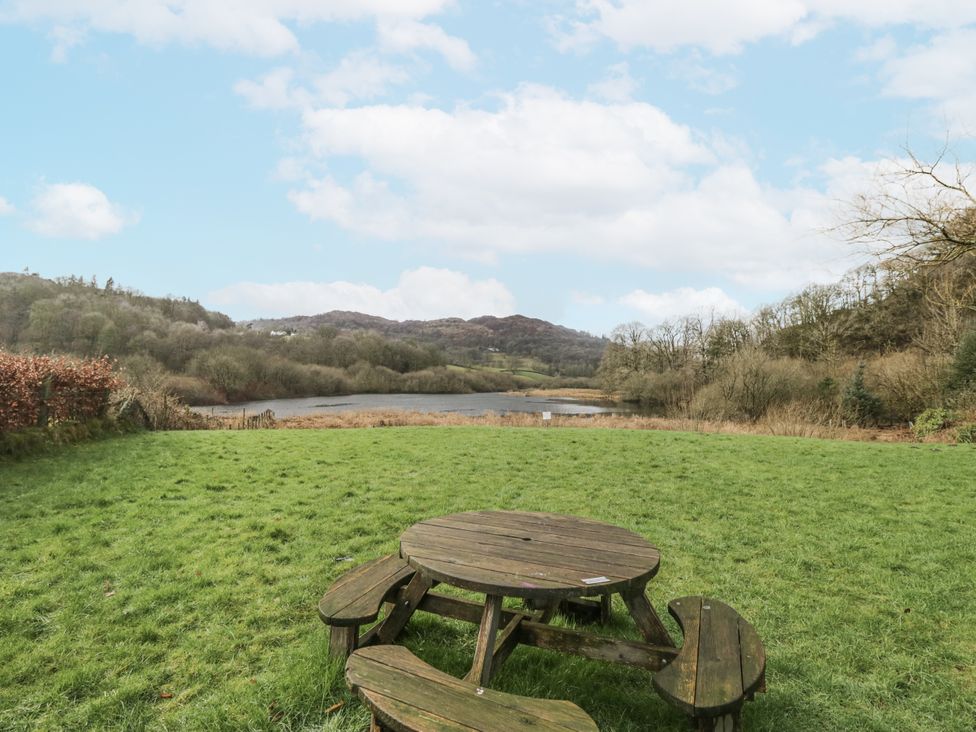 A garden with a wooden table and benches overlooking a lake at The Dove Cot in Ambleside