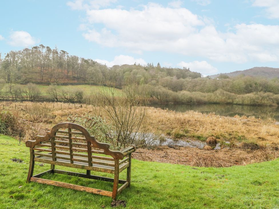 A bench overlooking a water body with trees at The Dove Cot in Ambleside