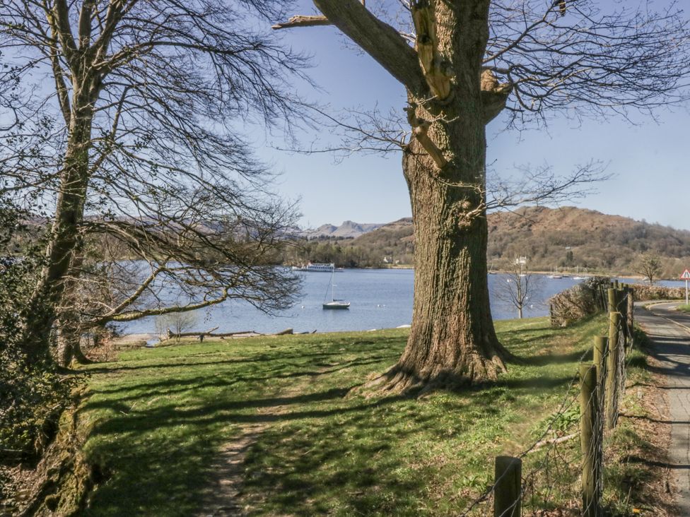 A lake with a boat and trees in the background at The Dove Cot in Ambleside