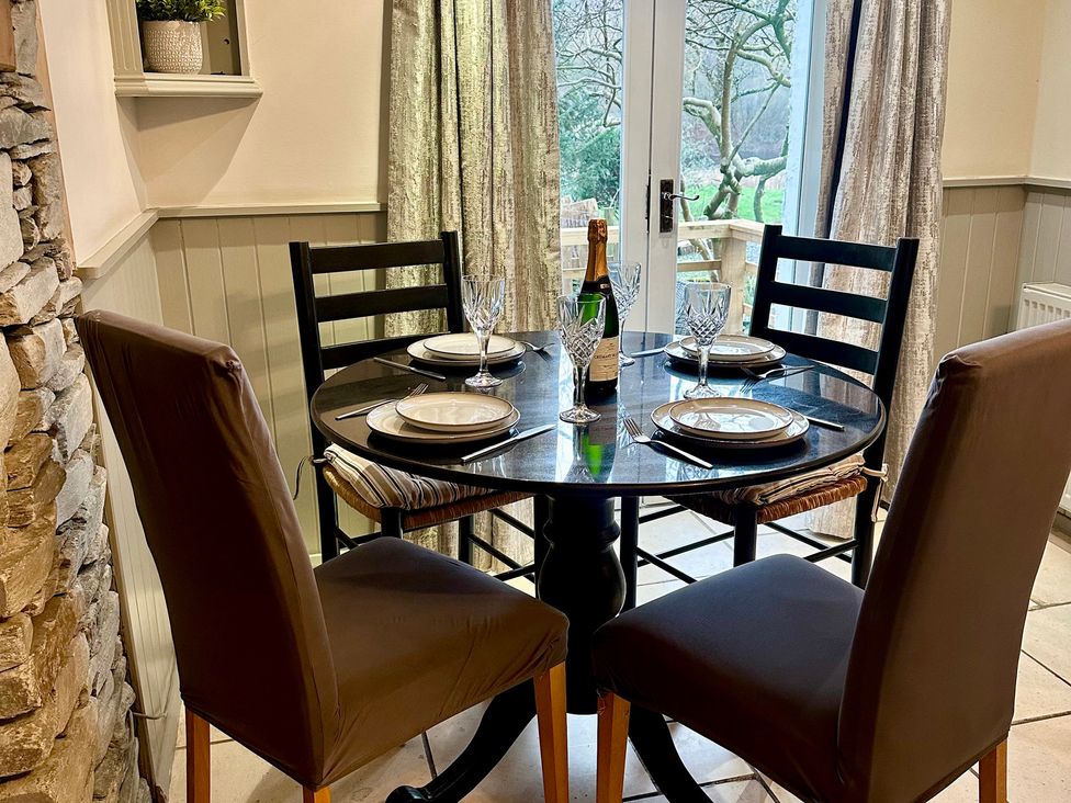 A dining room with a round table set for a meal at The Dove Cot in Clappersgate near Ambleside