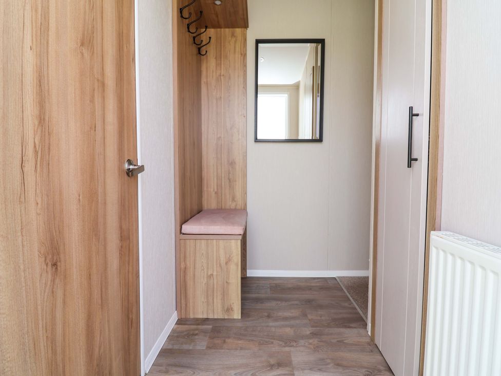 An entrance hall with a bench and mirror at Presthaven Sands in Prestatyn