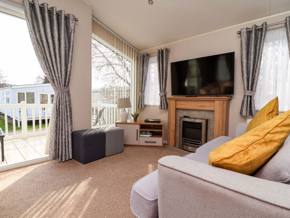 A living room with a television and sofa at Presthaven Sands in Prestatyn