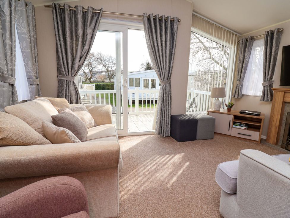 A living room with a sofa and a media cabinet at Presthaven Sands in Prestatyn