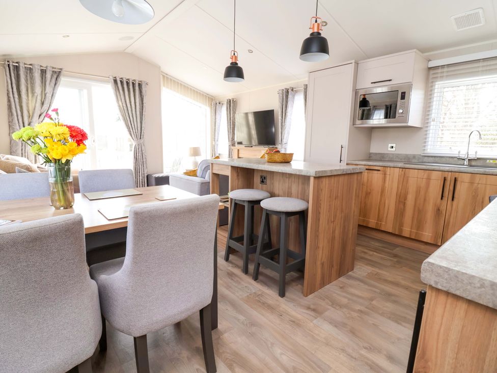 A kitchen with a dining table and bar stools at Presthaven Sands in Prestatyn