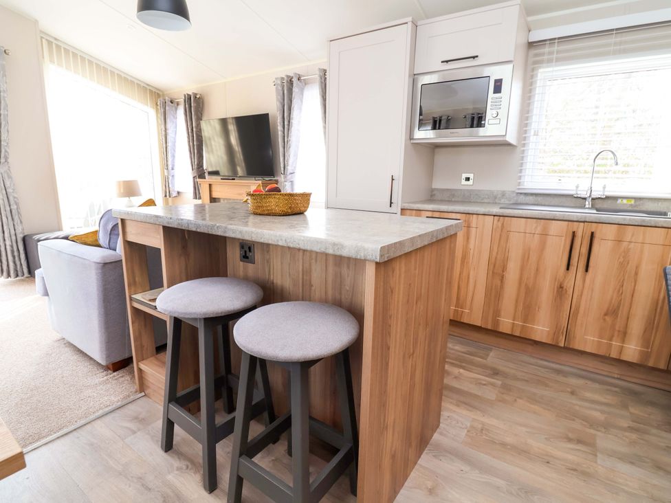 A kitchen with a counter and stools at Presthaven Sands, Prestatyn