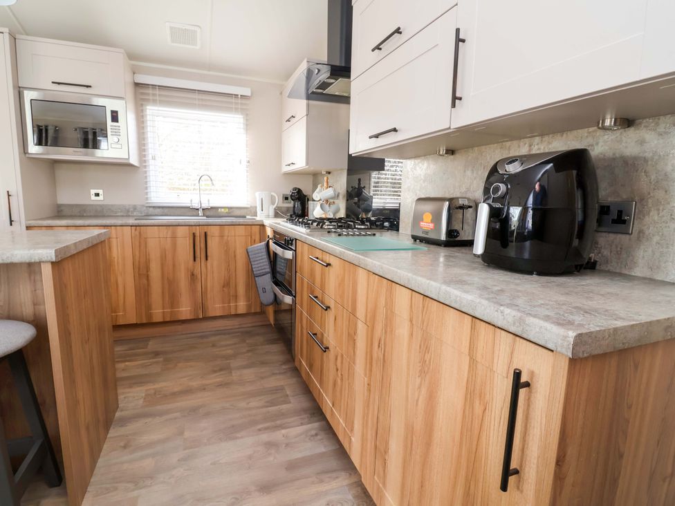 A kitchen with appliances and cabinets at Presthaven Sands in Prestatyn