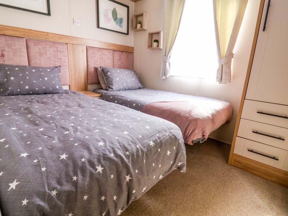A bedroom with two beds and a window at Presthaven Sands in Prestatyn