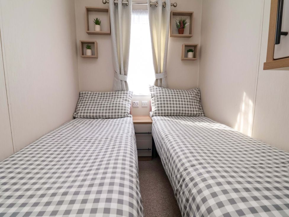 A bedroom with two beds and shelves at Presthaven Sands in Prestatyn
