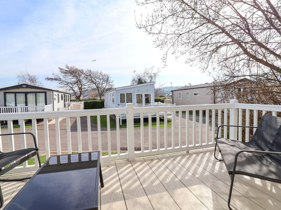A deck area with chairs and a table overlooking caravans at Presthaven Sands in Prestatyn
