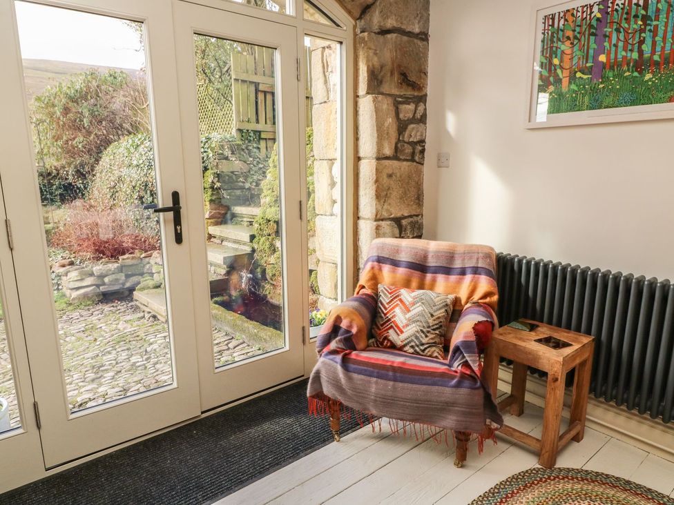 An entrance hall with an armchair and door leading outside at Litton Hall Barn Cottage, Skipton
