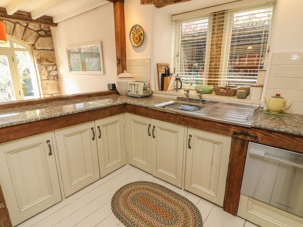 A kitchen with cabinets and a sink at Litton Hall Barn Cottage in Skipton