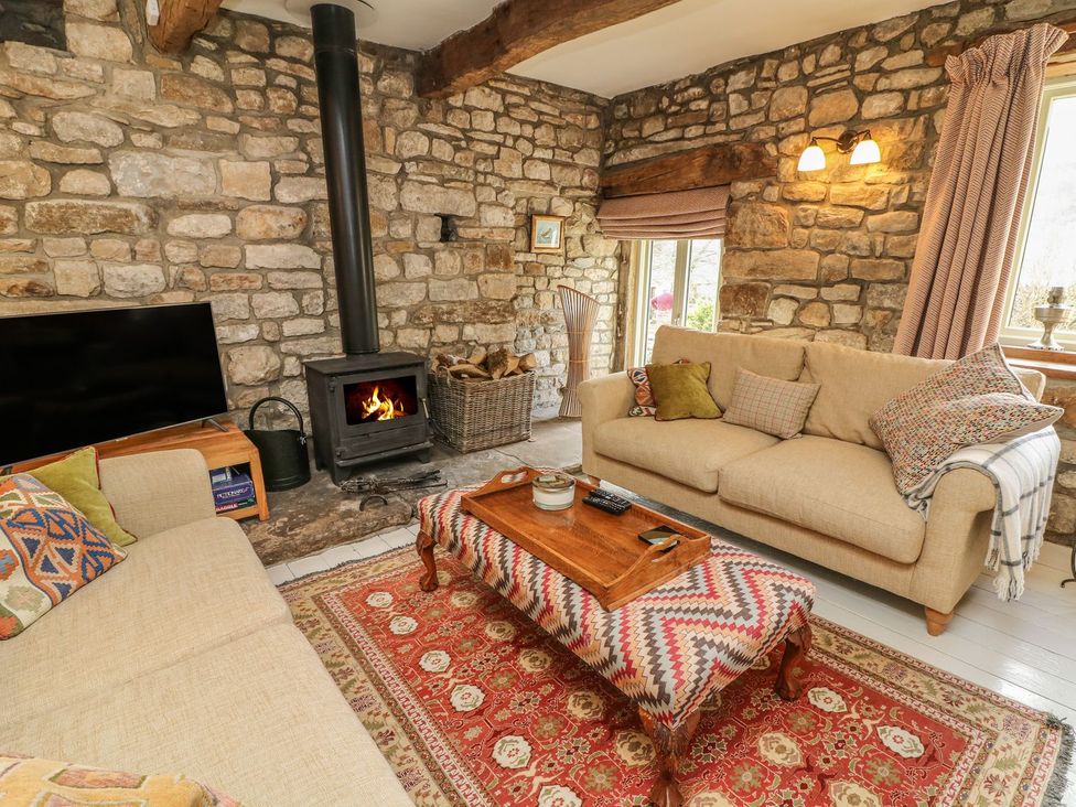 A living room with a fireplace and sofa at Litton Hall Barn Cottage in Skipton