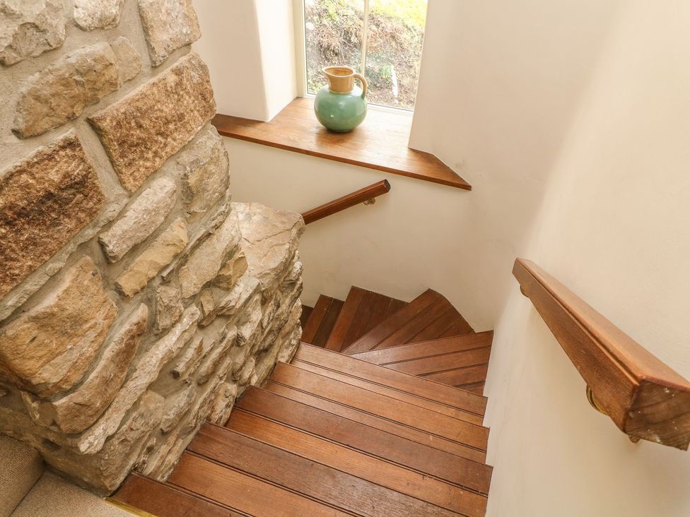 A wooden staircase with a stone wall and a ceramic vase at Litton Hall Barn Cottage Skipton
