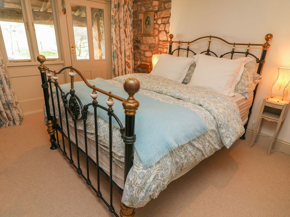 A bedroom with a bed and lamp at Litton Hall Barn Cottage, Skipton