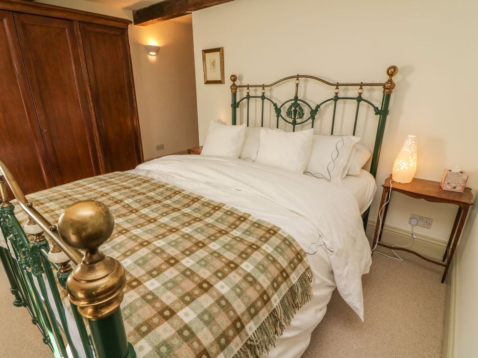 A bedroom with a bed and wardrobe at Litton Hall Barn Cottage in Skipton