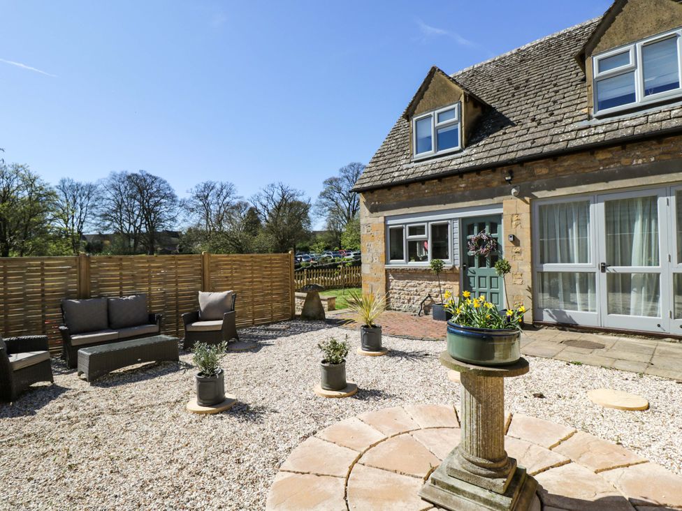 A garden with seating areas and planters at Paddock View in Stow-On-The-Wold