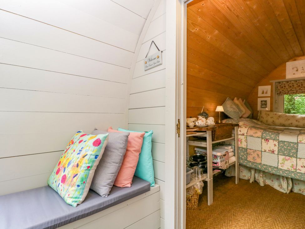 A bedroom with a bed and cushions at Daisy Glamping Pod in Woolton Hill