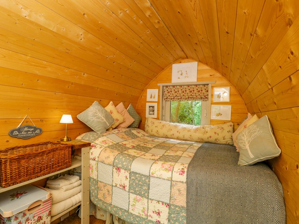 A bedroom with a bed and decorative pillows at Daisy Glamping Pod in Woolton Hill