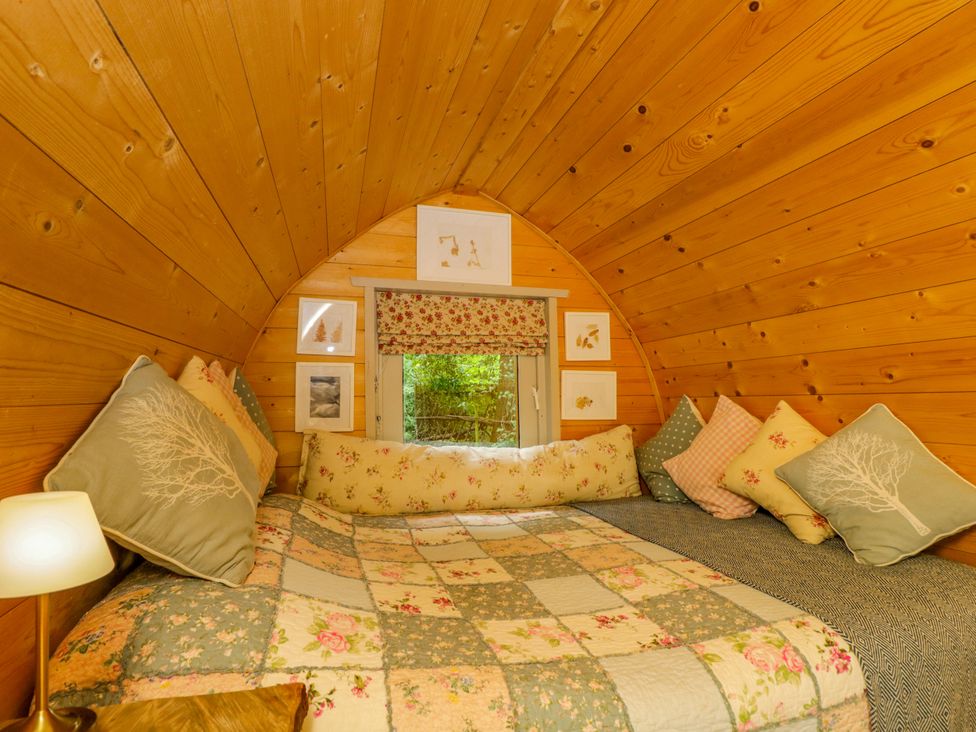 A bedroom with a bed and cushions at Daisy Glamping Pod Woolton Hill