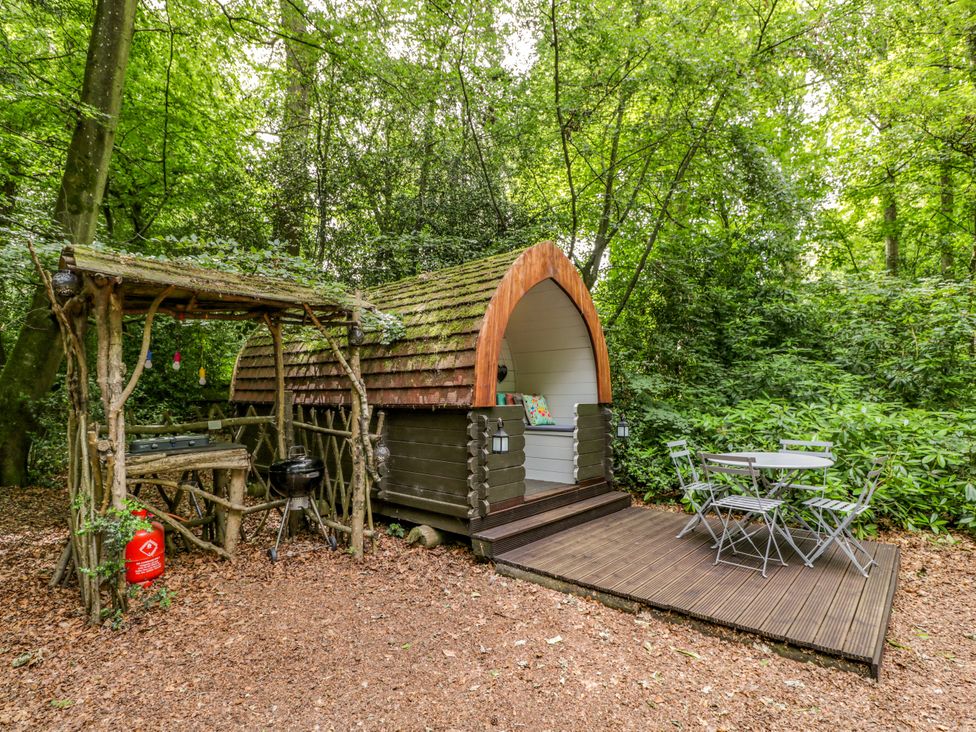 A glamping pod with an outdoor table and stool at Daisy Glamping Pod in Woolton Hill