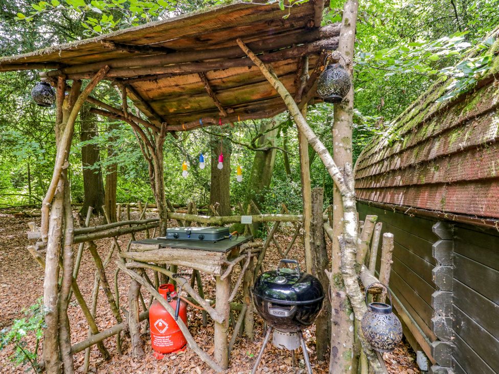 An outdoor cooking area with a wooden structure and grill at Daisy Glamping Pod in Woolton Hill