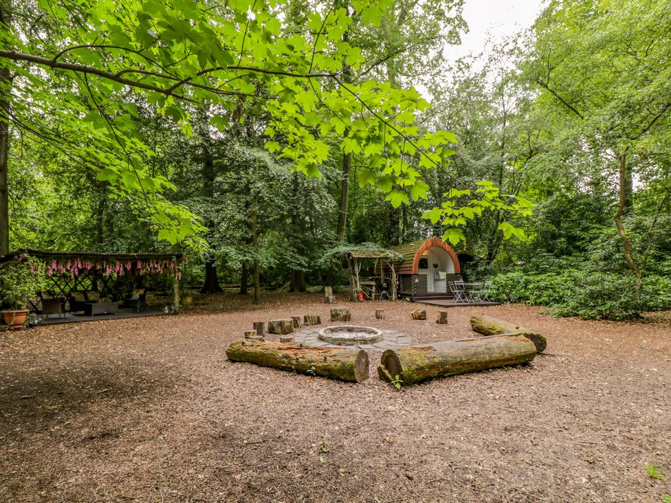 An outdoor area with a fire pit and seating logs at Daisy Glamping Pod Woolton Hill