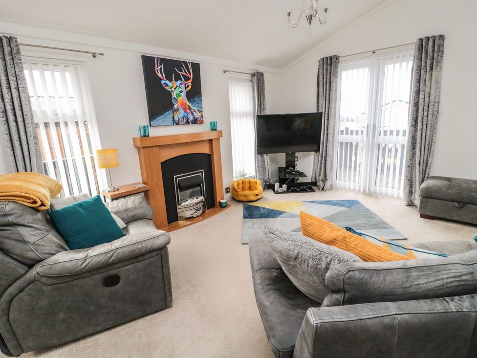 A living room with a television and fireplace at Nevaeh Lodge Longframlington