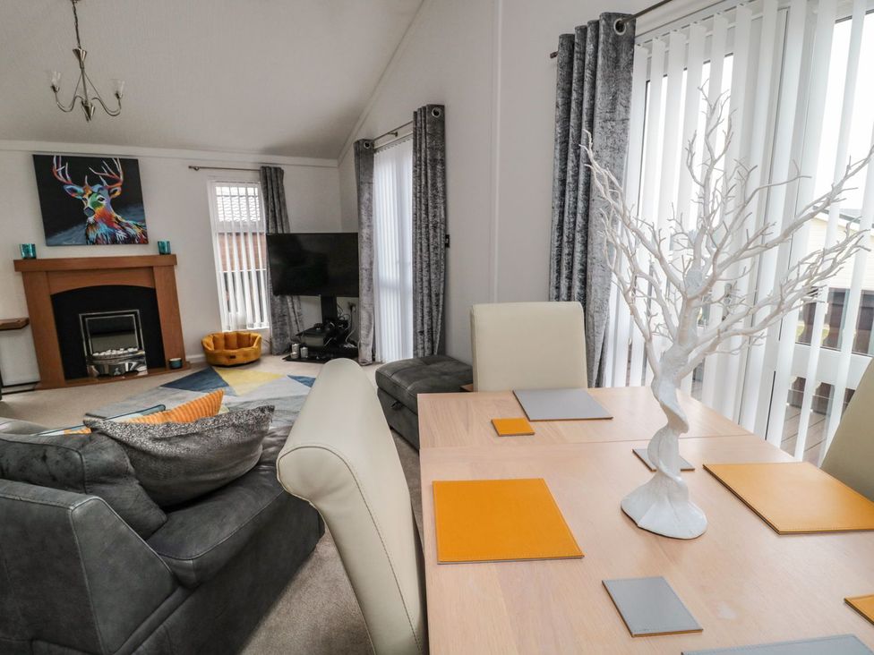 A living room with a dining table and sofa at Nevaeh Lodge Longframlington