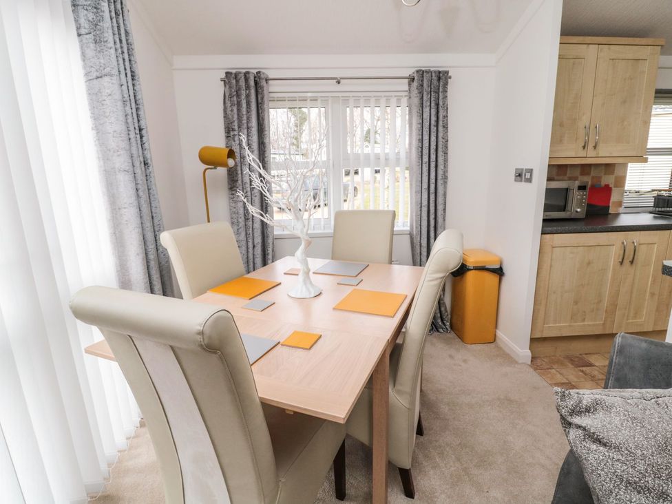A dining room with a table and chairs at Nevaeh Lodge in Longframlington