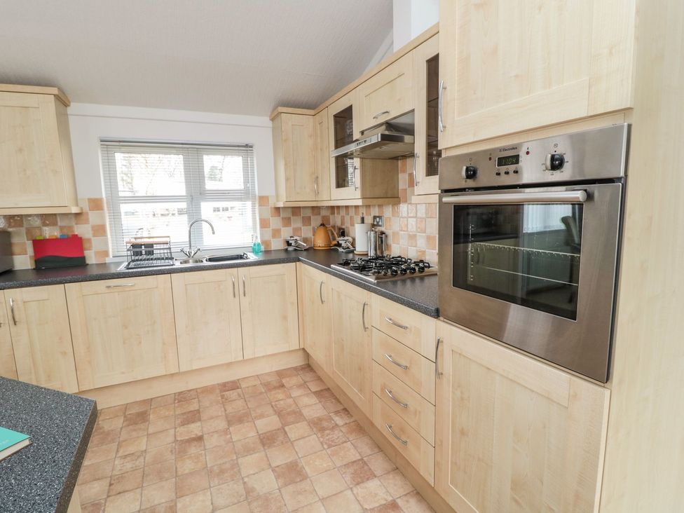 A kitchen with wooden cabinets and appliances at Nevaeh Lodge Longframlington