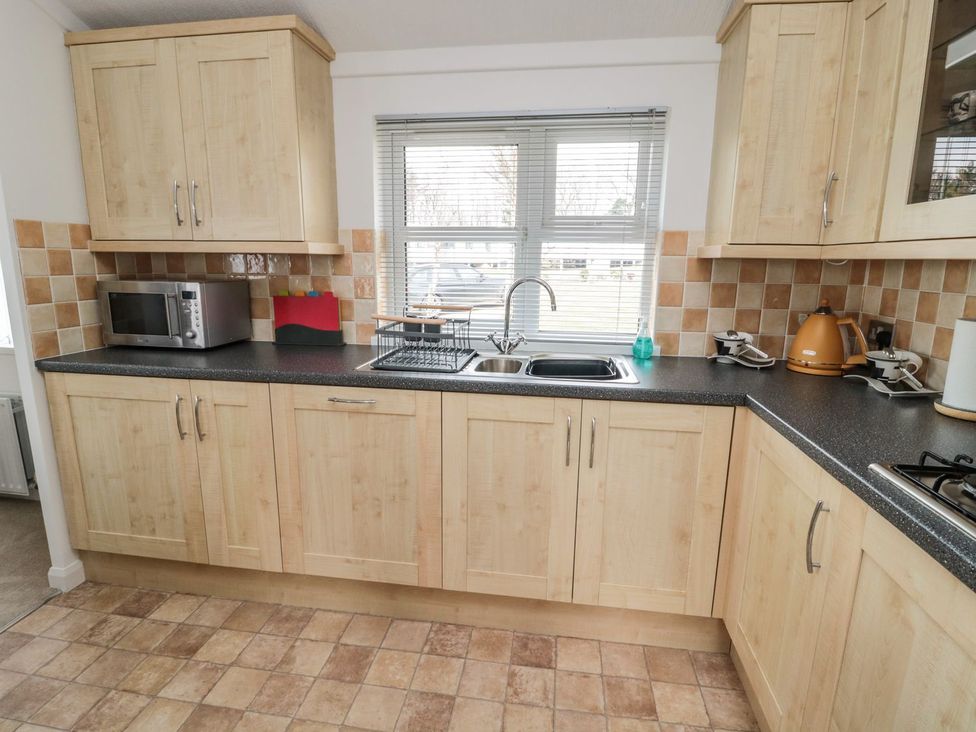 A kitchen with cabinets and sink at Nevaeh Lodge Longframlington